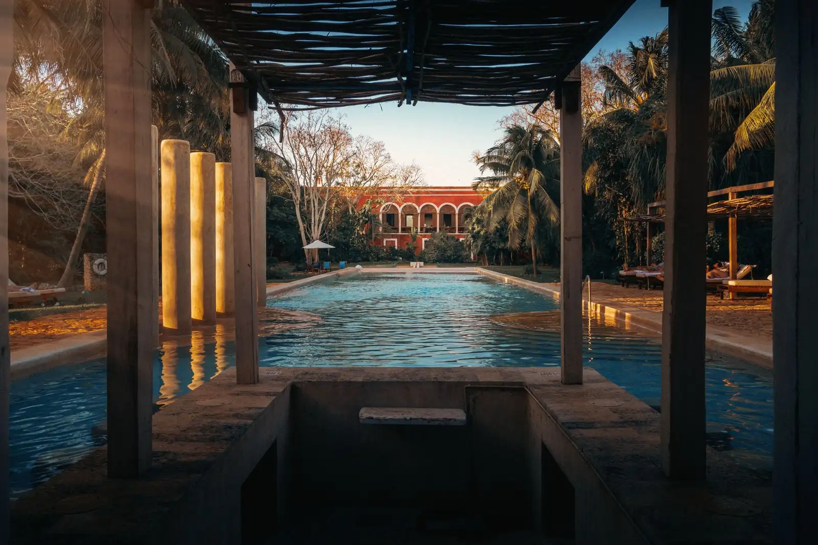 A tranquil pool view at a hacienda surrounded by lush greenery and colonial architecture.