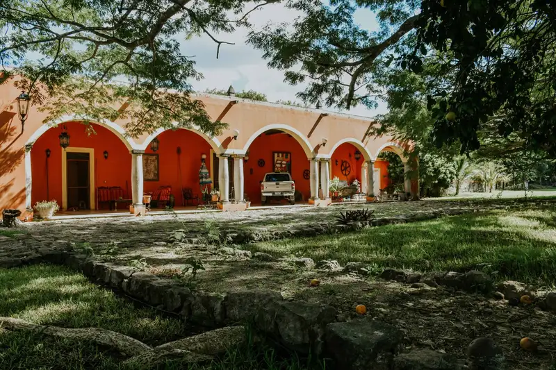Rustic hacienda with vibrant orange arches in a tranquil rural setting.
