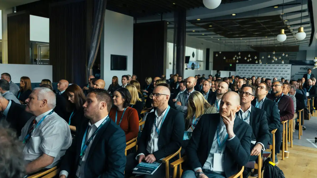 Engaged business professionals attentively listening at an indoor conference meeting in a retreat venue.