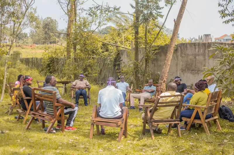 A group of adults having a team meeting outdoors in a garden during the day.
